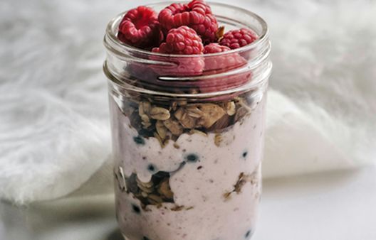 Healthy overnight oats recipe in a glass jar with chia seeds, granola and fresh raspberries for an easy make-ahead breakfast.