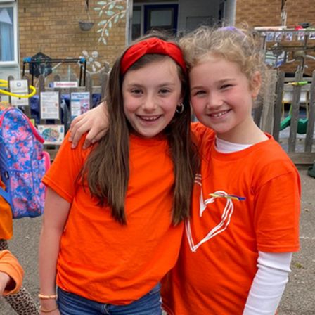 Two children on school playground wearing orange