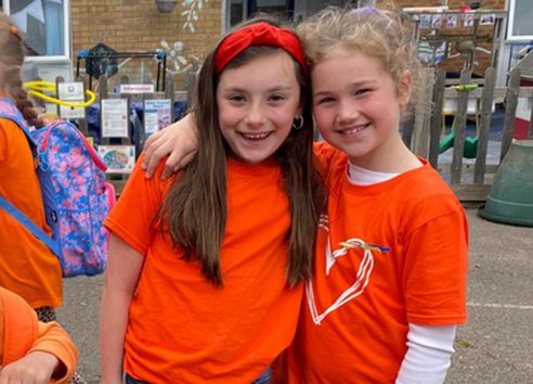 Two children on school playground wearing orange