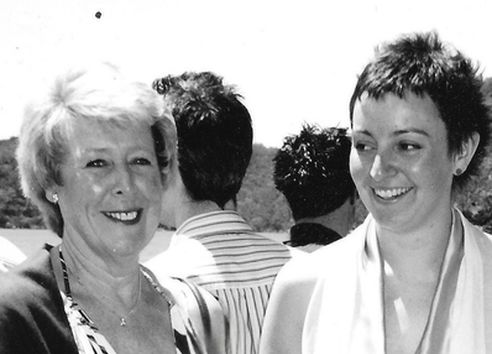 One blonde women and one brunette woman smiling in black and white