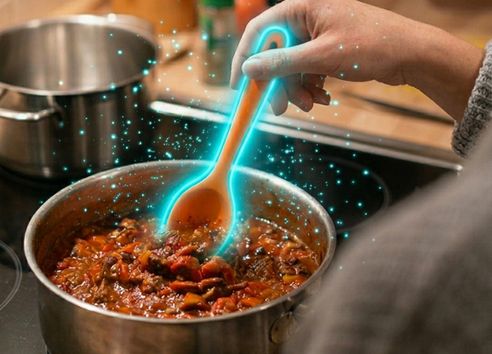 Metal suacepan with food in on electric hob with orange poon glowing blue