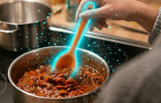 Metal suacepan with food in on electric hob with orange poon glowing blue