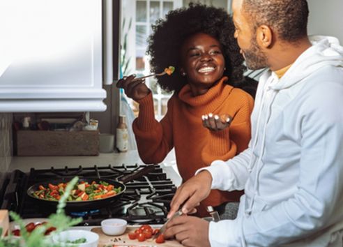 Couple cooking healthy stir fry vegetables together in their kitchen
