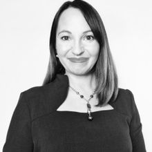 Women smiling in blazer and wearing a necklace in a black and white headshotAnne Roberts