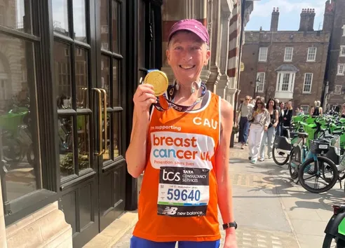 woman in breast cancer UK running vest holding medal in front of Lime bikes