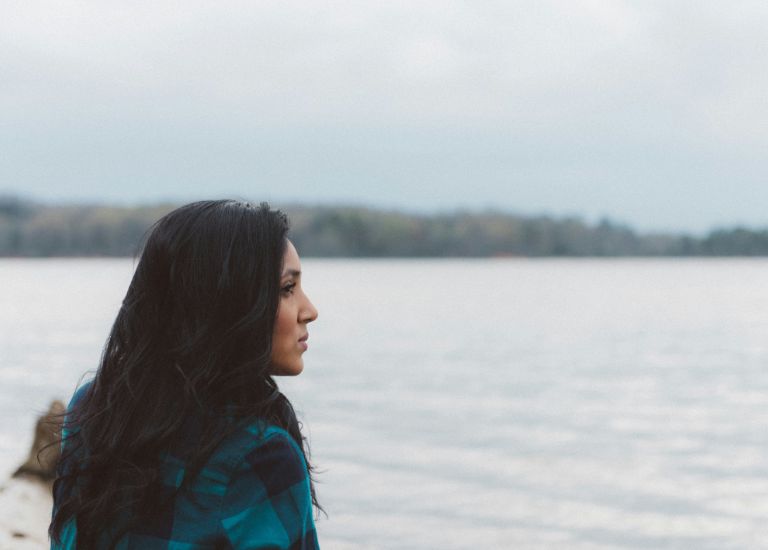 woman in coat looking out to sea