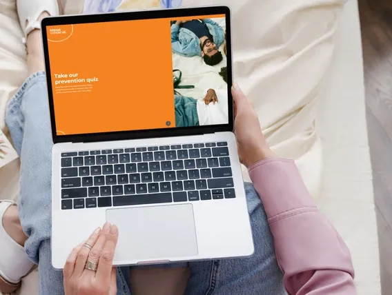 Woman sat on bed looking at laptop