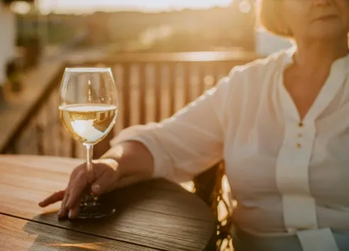 Woman sat at outside table holding white wine glass