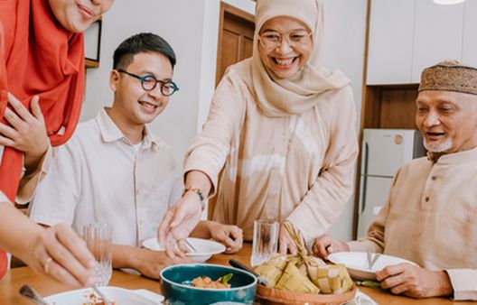 Muslim family gathered around the dinner table smiling