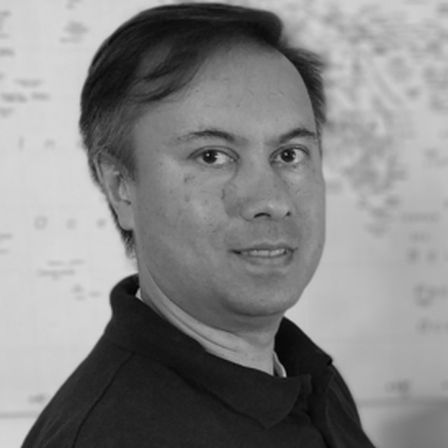 Man with brown hair in black and white head shot looking side on at the camera in black polo shirtDr Michael Jones