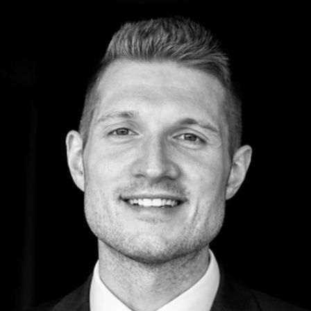 Man with short light brown hair in black and white head shot smiling at the cameraDr Dylan Peter McClurg