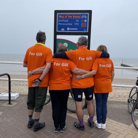 Four people on beach pier facing away from the camera in orange t-shirts that read for gill