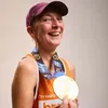 Female London marathon runner in Breast Cancer UK running vest holding medal