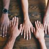 multiple diverse hands lying flat on a wooden table