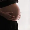 Woman holding pregnant belly in black clothing