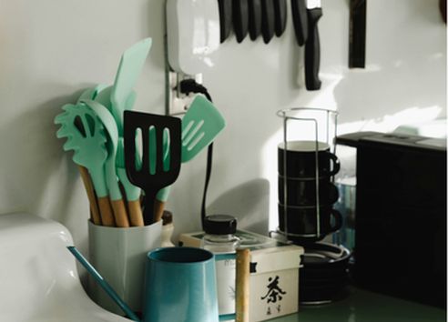 Cluttered kitchen side full of plastic untensils with green ends