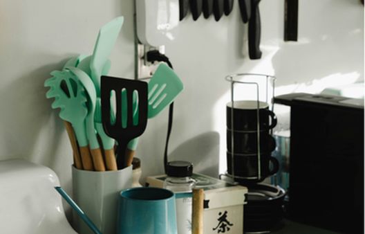 Cluttered kitchen side full of plastic untensils with green ends