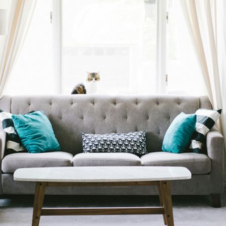 Grey sofa with blue cushions in a livingroom with coffee table in front of it