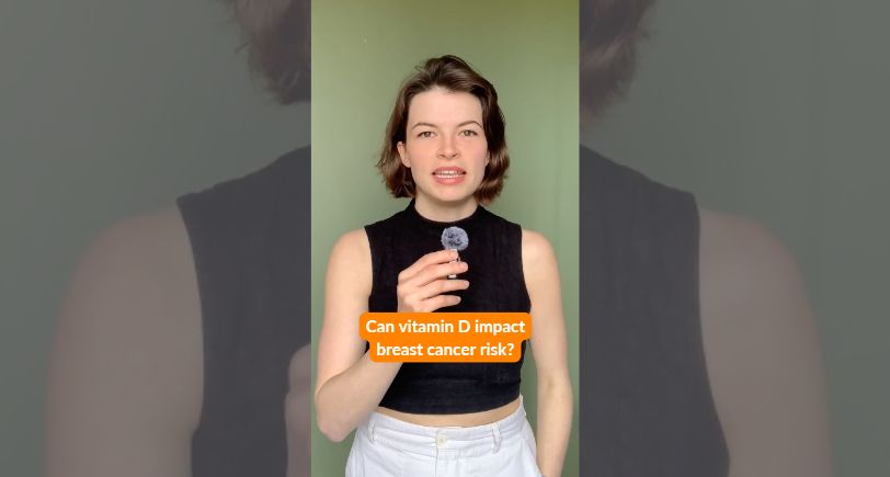 Video cover of woman with short brown hair in black vest top holding small microphone looking at camra orange captions on bottom of screen