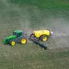 Green and yellow tractor spraying green fields