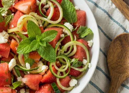 Top-down shot of a fresh strawberry, watermelon, cucumber, and feta salad with mint, featured in a healthy summer recipe by Breast Cancer UK.