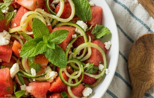 Top-down shot of a fresh strawberry, watermelon, cucumber, and feta salad with mint, featured in a healthy summer recipe by Breast Cancer UK.