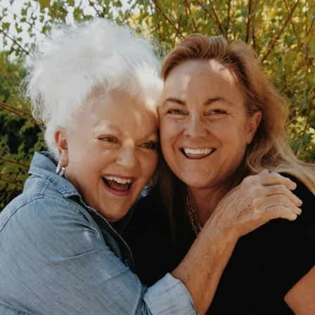 Older mother hugging adult daughter and laughing