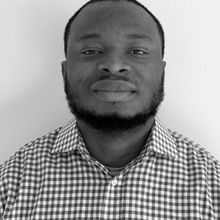 Man with shaved head in checkered shirt in black and white headshotFemi James