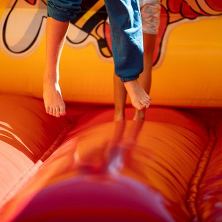 Children's feet on orange and yellow bouncy castle inflatable
