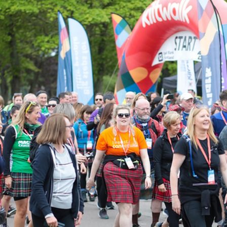 People in crowd walking the kiltwalk and centre woman wearing Breast Cancer Uk t-shirt