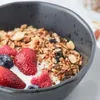 Black bowl of granola with yoghurt and fruit
