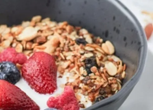 Black bowl of granola with yoghurt and fruit