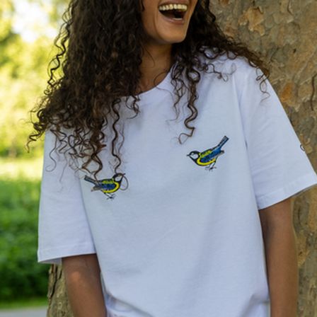 woman with curly hair in white t-shirt in front of a tree