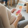 Pregnant woman holding leaflet with pregnant mother on cover in pink top ginger hair