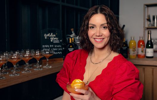 Headshot of Camille Vidal holding her Golden Glow cocktail at Breast Cancer UK Full Supper Club Launch