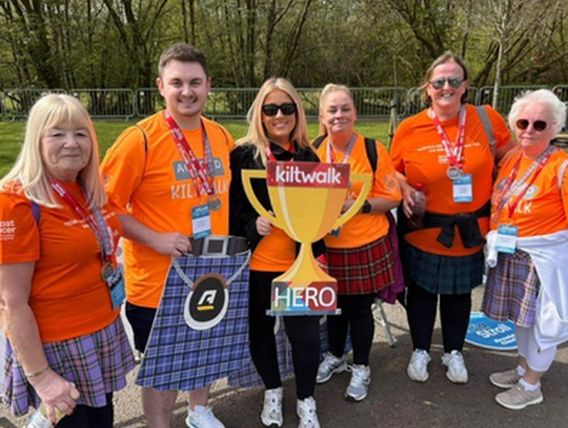Group of people holding cardbaord trophy sign in ornage t-shirts and wearing medals