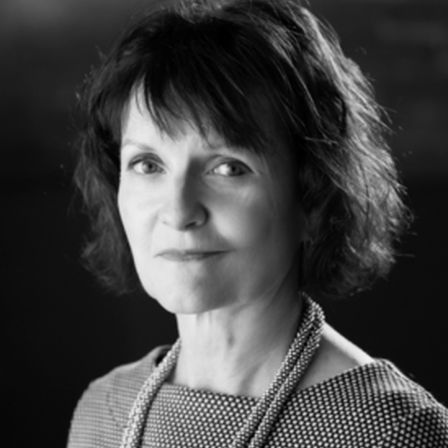 Woman with short brown hair and necklace around neck in black and white headshotAnne Lloyd