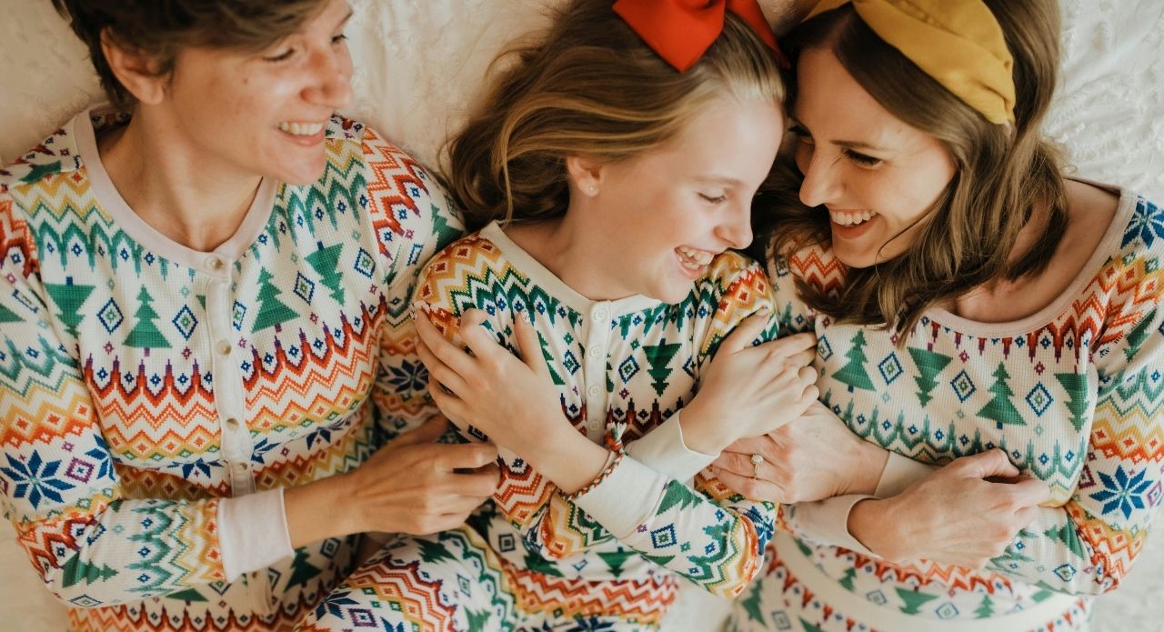 two women and young girl in matching Christmas pyjamas laying on a bed